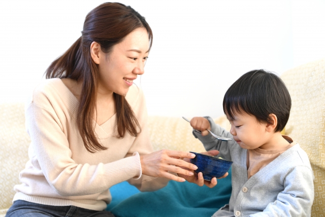 笑顔でご飯を食べる子供と見守る母親